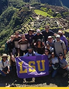 LSU School of Nursing students carrying an LSU banner, with the backdrop of Machu Picchu ruins in Peru.