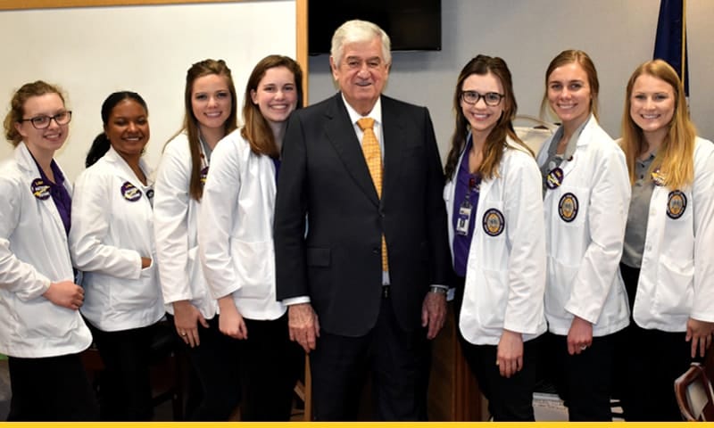 Louisiana Senate President John Alario posing with seven LSU Health New Orleans School of Nursing students.