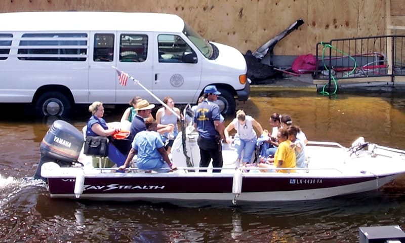 Nurses and other health care professionals in a motorboat navigating a flooded New Orleans street after Hurricane Katrina.