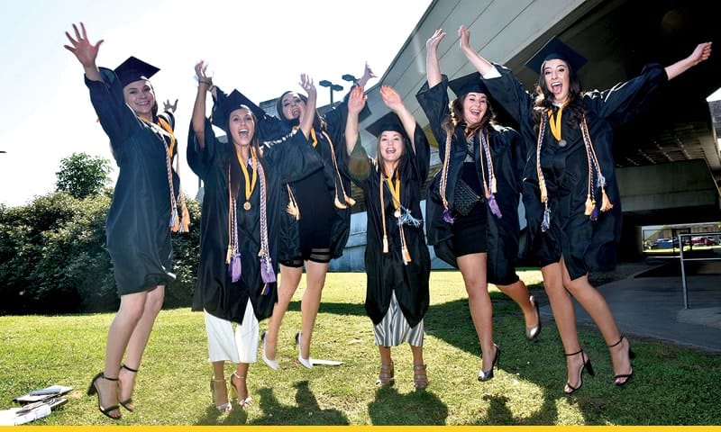 Group of graduates in caps and gowns waving their hands