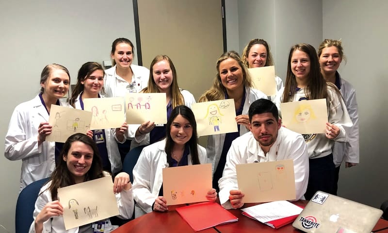 11 LSU School of Nursing students showing their illustrations of their experiences in their population health courses.