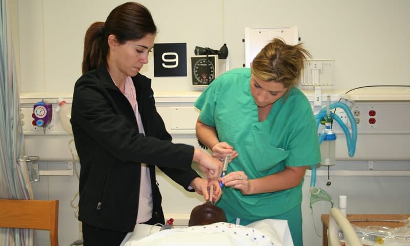 Two women working on a surgical dummy