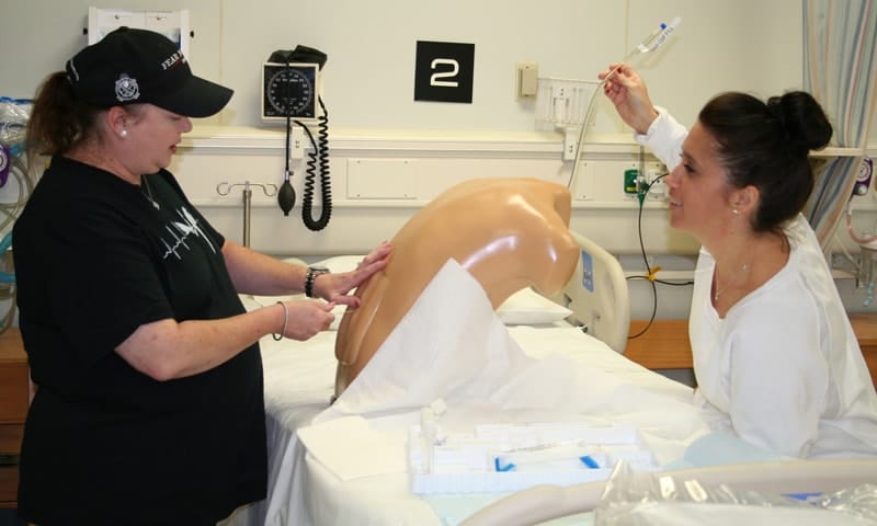Two women performing on medical dummy