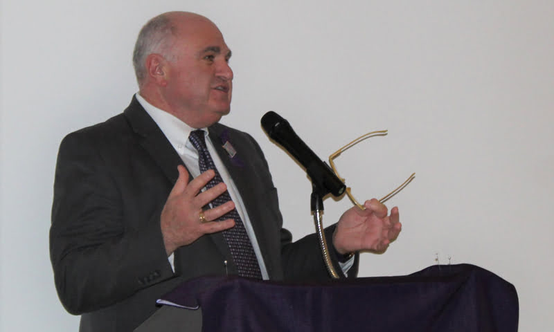 Dean Demetrius Porche speaks into a microphone at a podium.