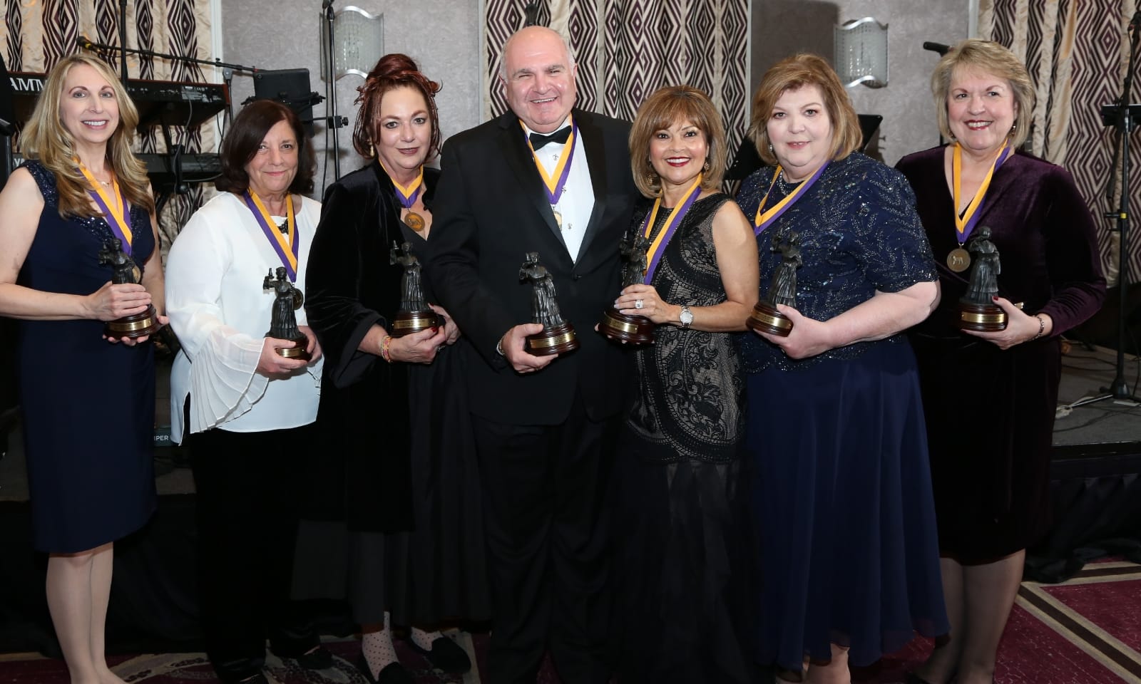 A group of people smile while holding awards.