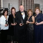 Six women and one man smile and pose holding Florence Nightingale statues.