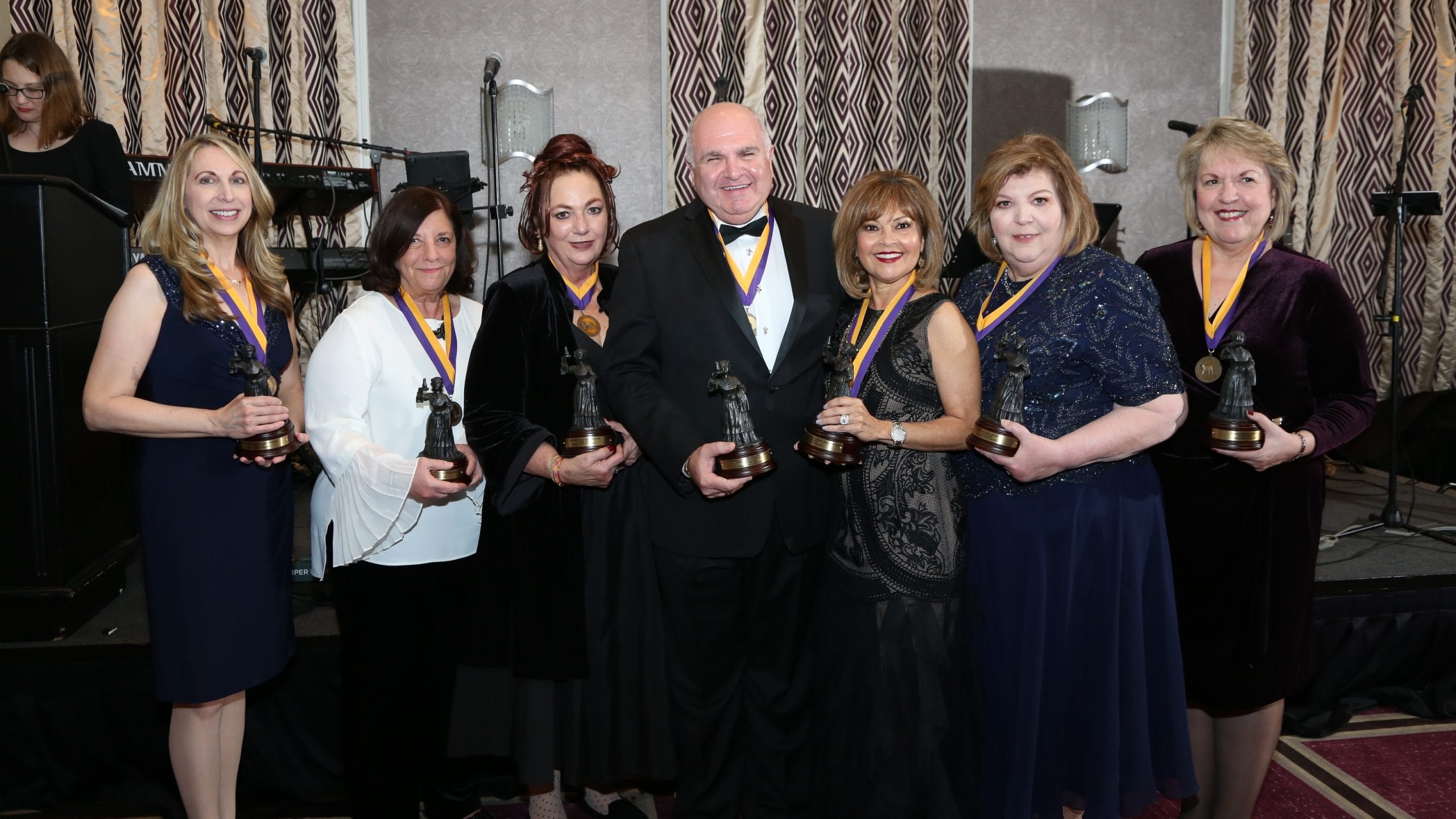 Six women and one man smile and pose holding Florence Nightingale statues.