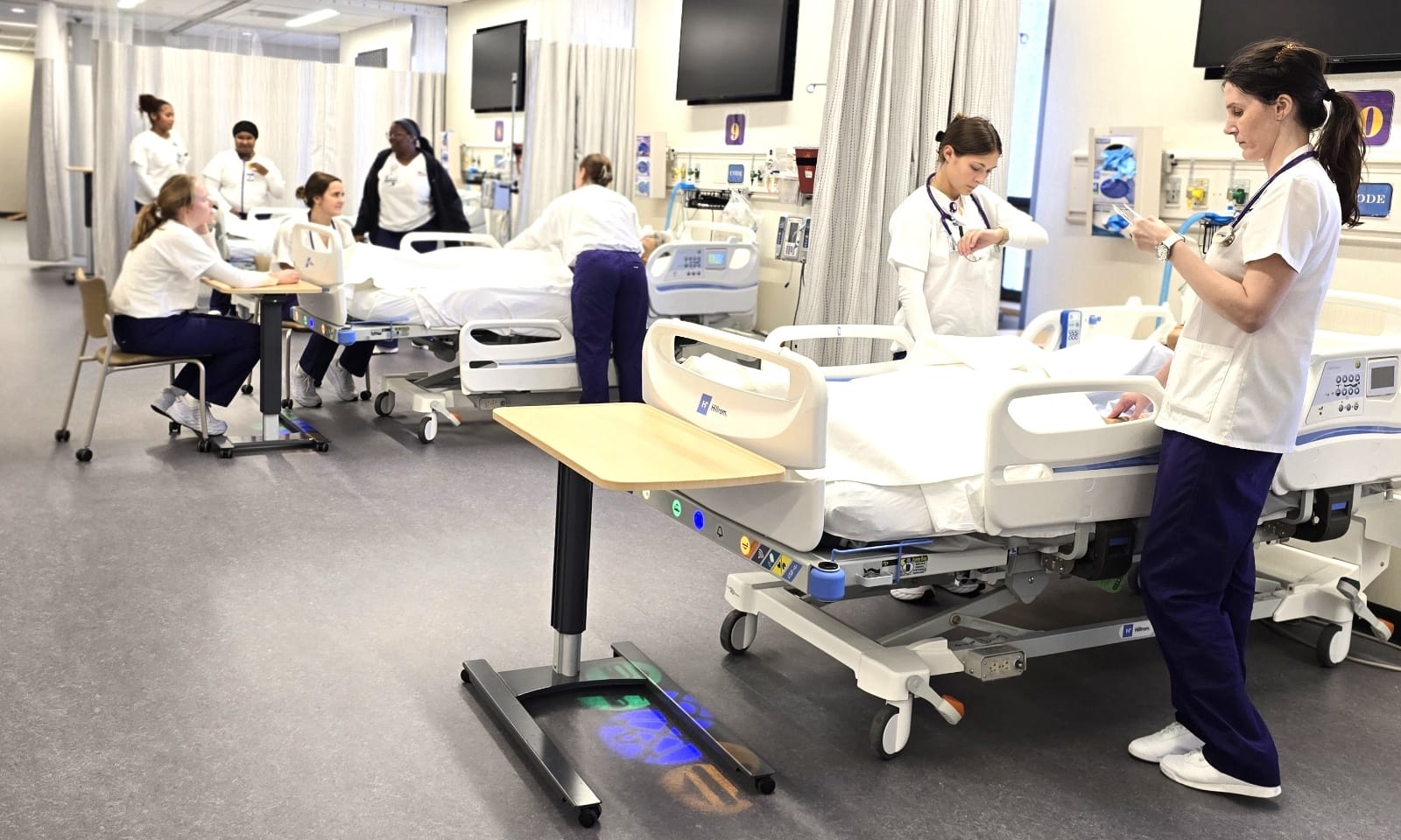 Three young women take vital signs of a simulated patient mannequin.