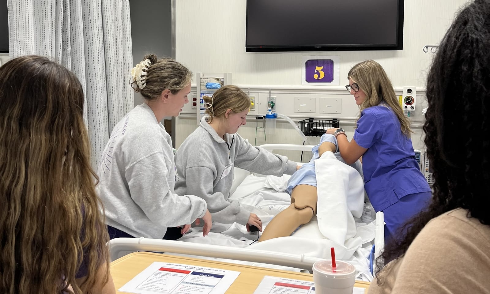 New nursing students work together on an anatomy simulation table.
