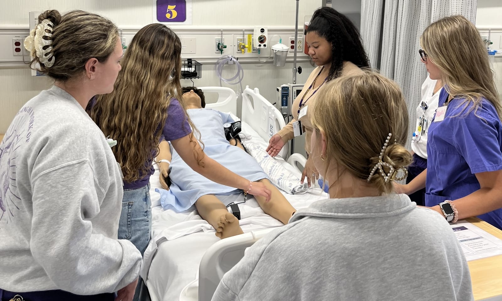 New nursing students work together on an anatomy simulation table.