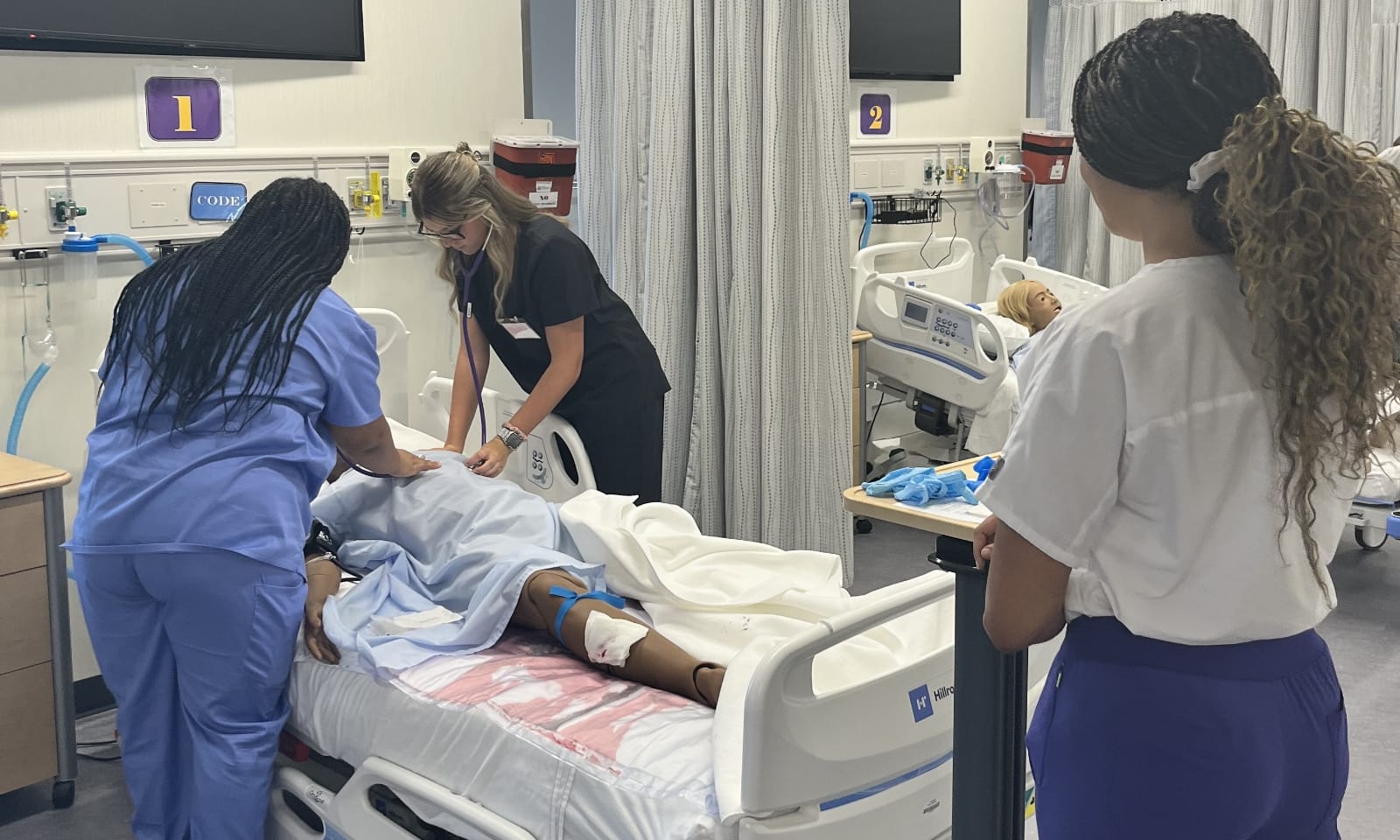 New nursing students work together on an anatomy simulation table.