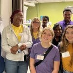 A diverse group of high school students work with nursing students and faculty on simulations and lessons .